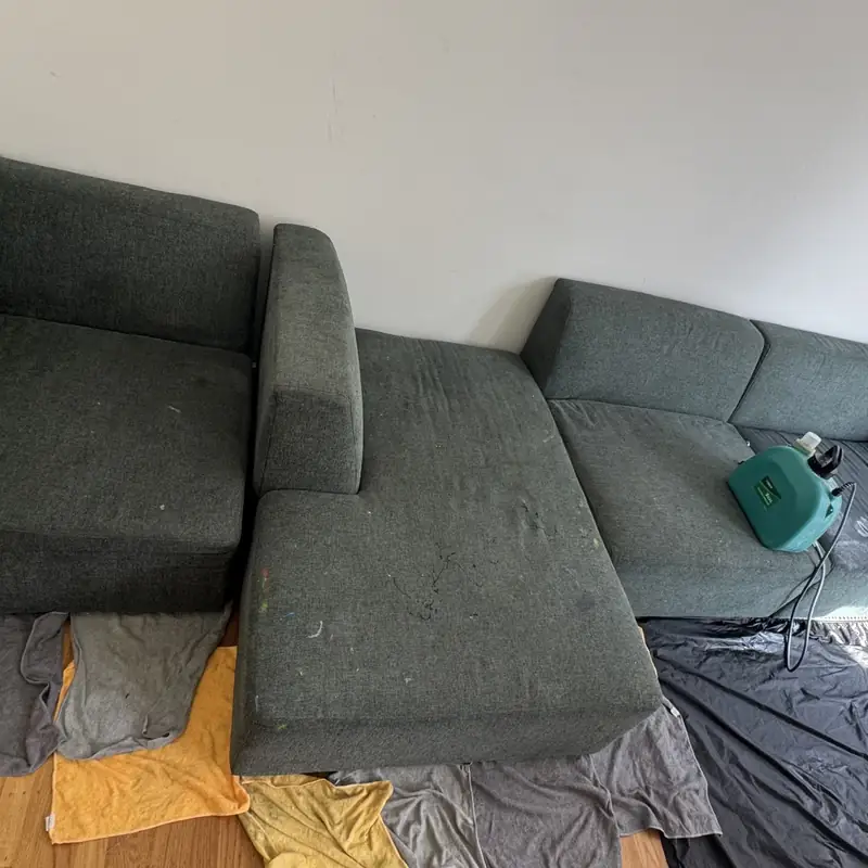 Charcoal sectional with cushions removed and floor protected before deep cleaning