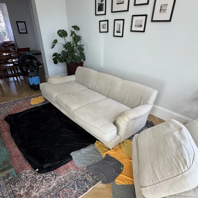 Cream sofa with cushions removed and floor protected before cleaning