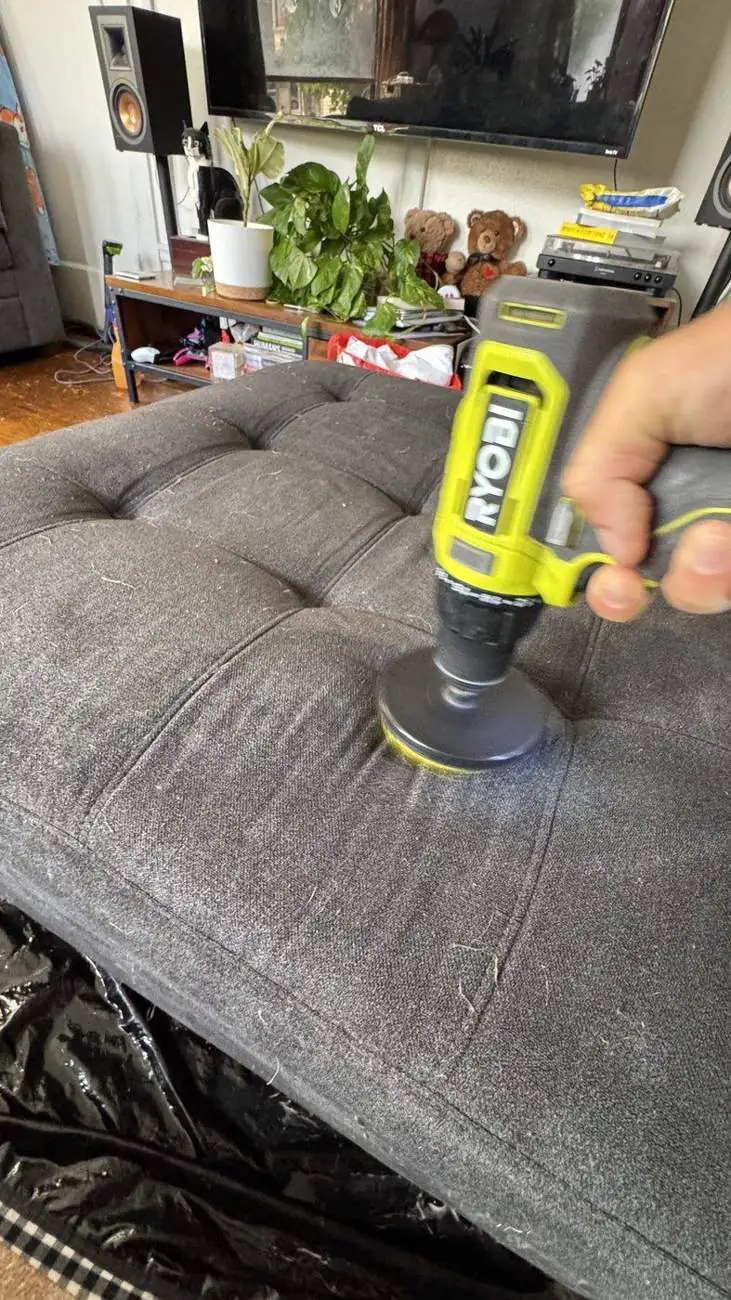 Deep cleaning the gray sectional ottoman with an extraction tool