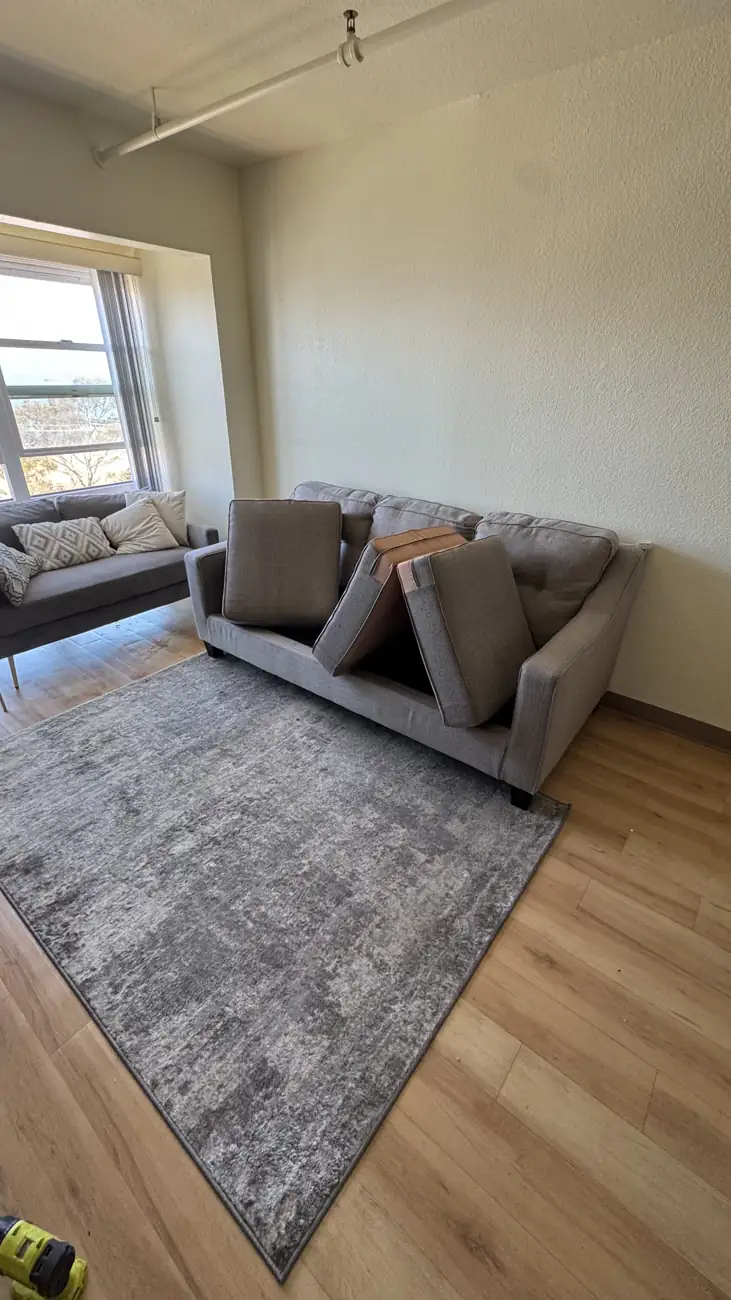 Light grey tufted sofa after deep cleaning, placed back in the living room