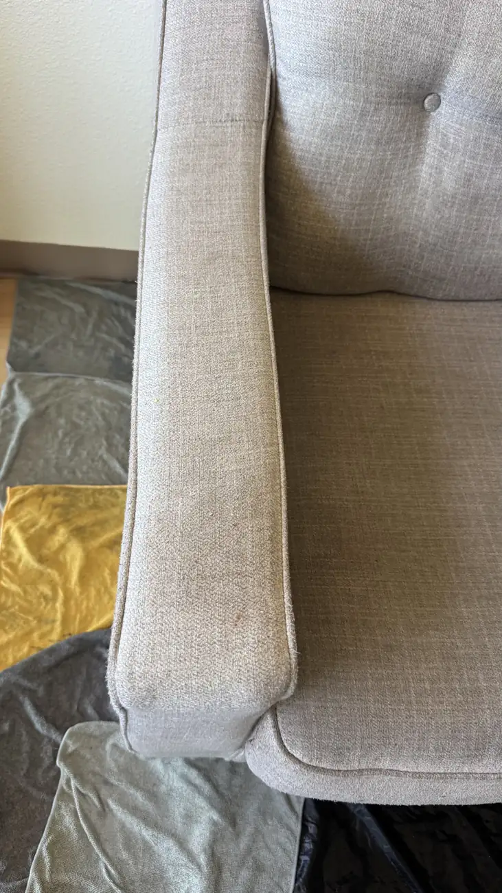 Close-up of button tufting on a grey sofa during cleaning